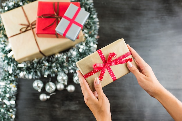 Christmas gifts on a table with black and hands holding present