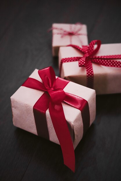 크리스마스 선물과 전통적인 휴일은 계절 휴일을 위한 빨간 리본 빈티지 소박한 시골 스타일로 공예 종이에 싸인 나무 배경에 있는 고전적인 xmas 선물 상자를 선물합니다.
