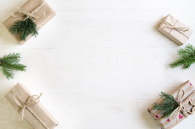 Christmas gifts on a white wooden background with tree branches. 