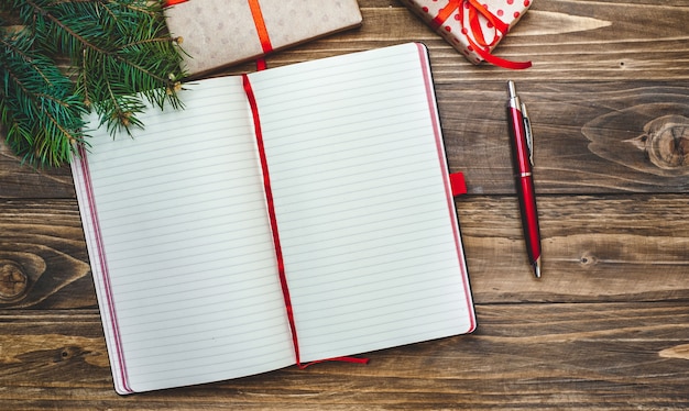 木の板に装飾が施されたクリスマスプレゼントとレコード用のペンが付いたノート