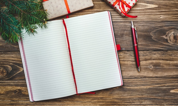 Christmas gifts with a decoration on a wooden board and a notebook with a pen for records