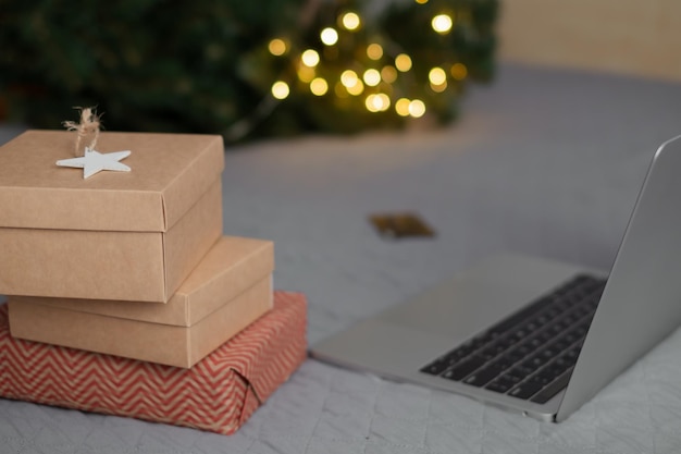 노트북 배경의 침대에 장식용 별이 있는 크리스마스 선물과 온라인 쇼핑 조명