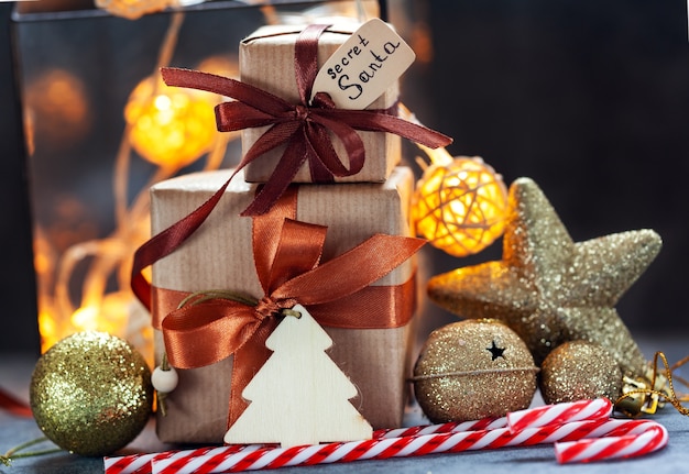 Regali di natale avvolti in carta artigianale con decorazioni natalizie e luci su sfondo scuro