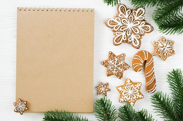 Christmas gingerbread and brown notebook on white wooden table