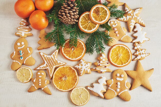 Christmas gingerbread cookies and dried orange and spices on white table. Chairs Christmas trees, cones and Christmas decorations