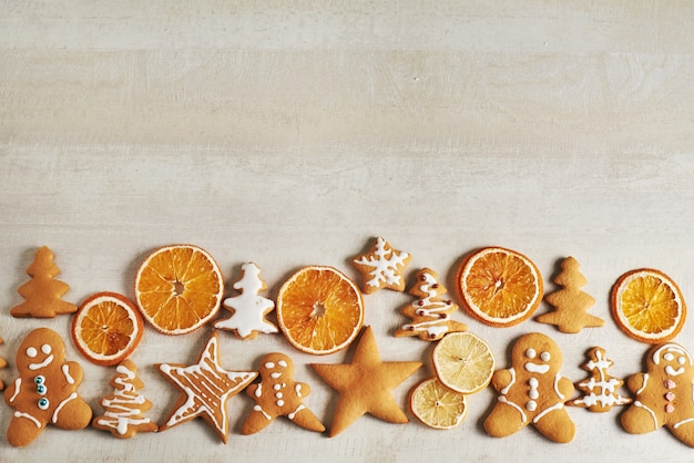 クリスマスジンジャーブレッドクッキーと乾燥したオレンジと白いテーブルの上のスパイス