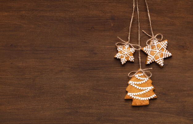 コピースペースで木製の背景にぶら下がっているクリスマスジンジャーブレッドクッキー