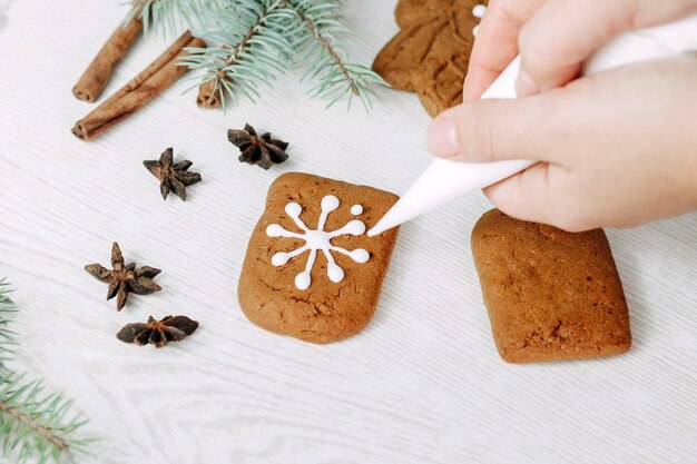 설탕을 입힌 크리스마스 진저 쿠키. 과자 장수 소녀가 쿠키를 그립니다.