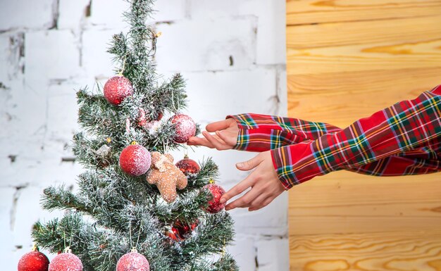 Christmas, a girl decorates a holiday tree. Selective focus. Holiday.