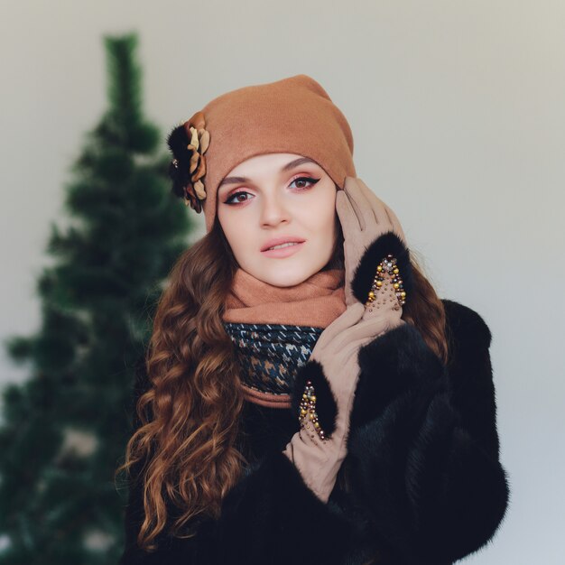 Рождественская девочка в вязаной теплой шапке и варежках, изолированных на сером