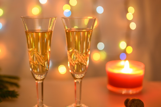 燃えるろうそくと暖かい色の輝く花輪の背景にクリスマスグラス。