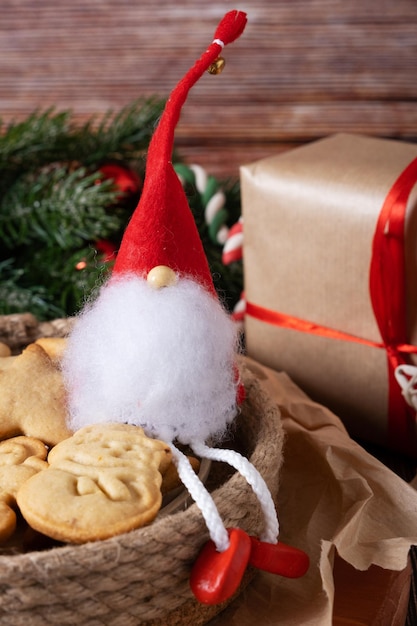 A Christmas gnome in a red hat closeup sits in a plate with homemade cookies