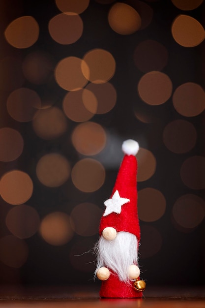 焦点がぼけたライトの暗い背景に赤い帽子をかぶったクリスマスのノーム