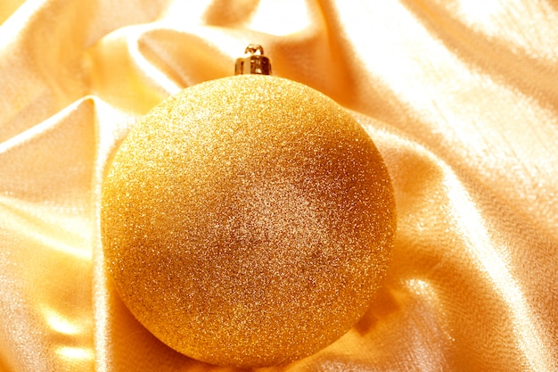 Christmas gold glitter bauble on golden fabric