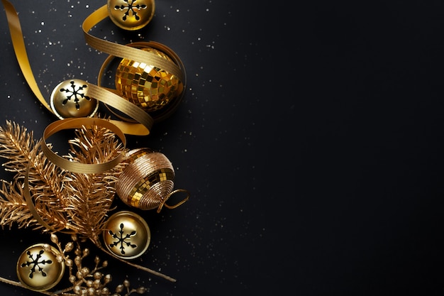 Photo christmas golden baubles on dark background. flat lay.