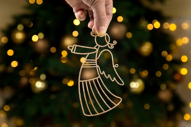 Christmas golden decorations, angel in hand on tree