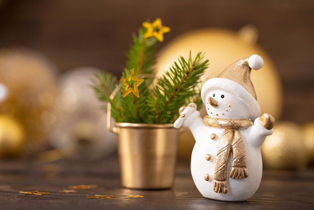 Christmas golden decorations and snowman on dark wooden background