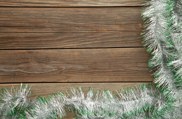 Christmas green and silver tinsel on grey wooden background. Top view.