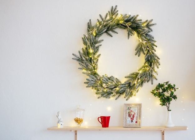 Ghirlanda di natale verde e altre decorazioni, a luci gialle su sfondo bianco