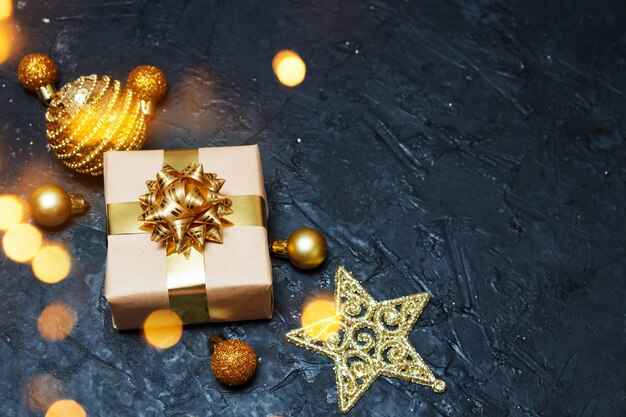 Photo christmas greeting card composition. gift with golden christmas decoration with light on dark blue background