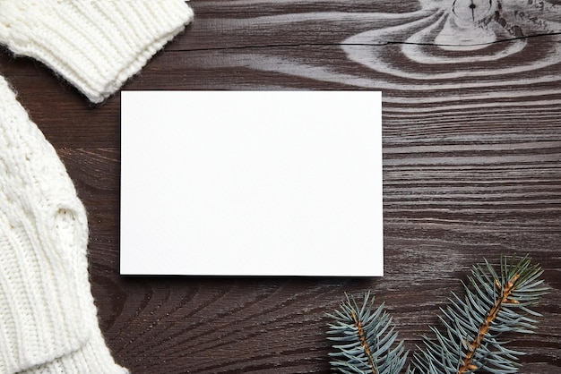 Photo christmas greeting card mockup with green fir tree branches and knitted sweater on brown wooden background top view flat lay blank new year holiday card mock up with decoration