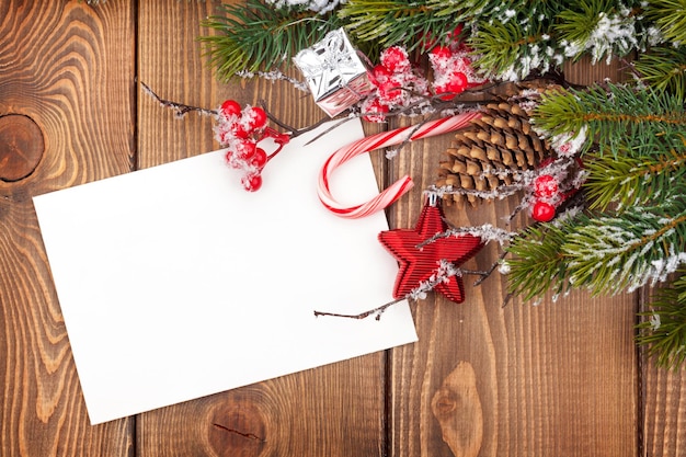 雪モミの木と木製のテーブルの上のクリスマスグリーティングカードまたはフォトフレーム