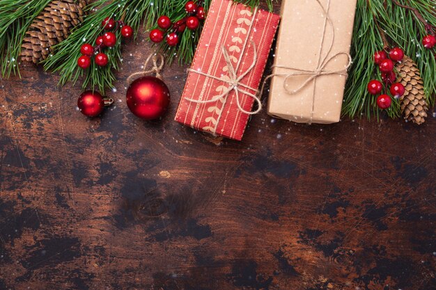 Christmas greeting card with fir tree branch, gifts and present box. Wooden background. Top view copyspace. Snow effect
