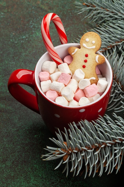 Christmas greeting card with fir tree and cacao cup with marshmallow candy cane and gingerbread man