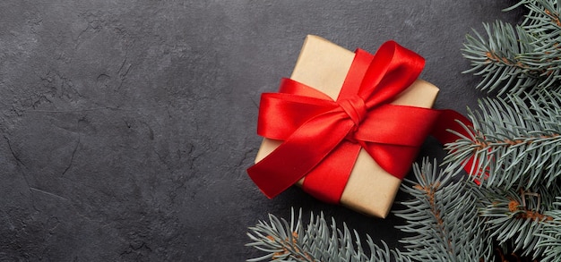 Рождественская поздравительная карточка с еловой елкой и подарочной коробкой на каменном фоне и копировать пространство для ваших рождественских поздравлений Верхний вид плоский