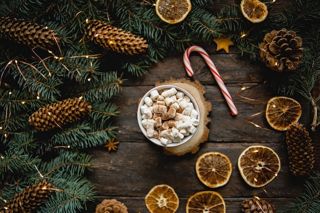 Christmas greeting card with fir tree and hot chocolate with marshmallow on wooden table Top view