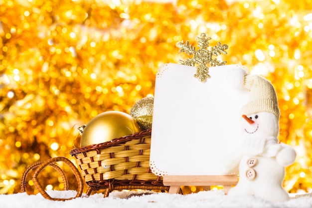 Christmas greetings with snow, snowman and sledge over gold sparkle background