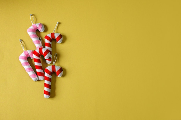 Christmas handmade felt candy cane on yellow background with copy space, Christms handmade felt ornaments
