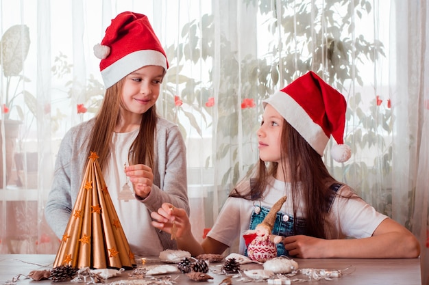 Natale fatto a mano. le ragazze decoreranno un albero di natale fatto in casa con giocattoli di legno