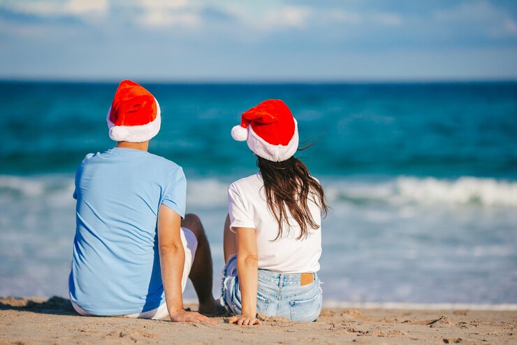 Photo christmas happy couple in santa hats on beach vacation