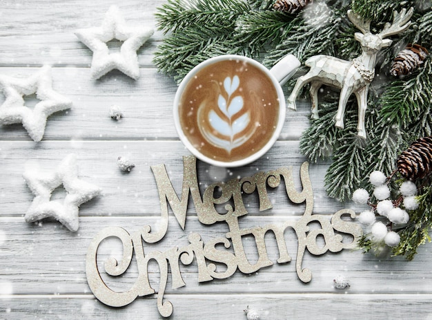 Рождественская и счастливая новогодняя открытка с чашкой кофе, сосной, пихтой на белом деревянном фоне, вид сверху
