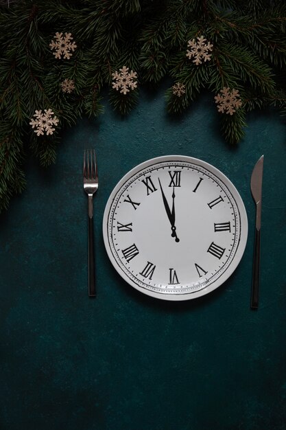 Christmas and Happy New Year Festive background with fir tree branches, christmas decoration and clock that shows New Years Eve