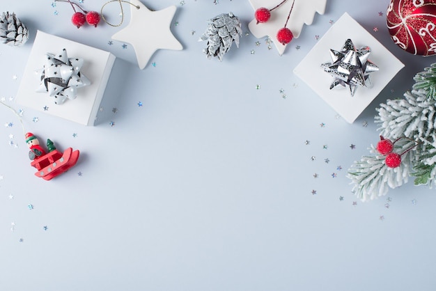 Рождества и счастливого нового года плоская открытка с подарочной веткой и серебряным украшением на белом и синем фоне копией пространства вид сверху