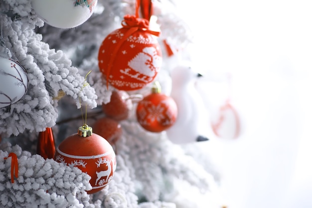 Priorità bassa di festa di natale. pallina d'argento e di colore appesa a un albero decorato con bokeh e neve, spazio copia.