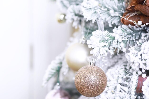 Christmas holiday background. Silver and color bauble hanging from a decorated on tree with bokeh and snow, copy space.