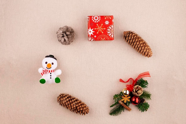 Christmas holiday background with decor laid out in a circle pine cones gift snowman on a linen fabric background flat lay copy space