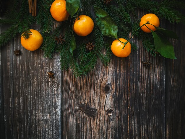 Рождественская открытка с мандаринами и еловыми ветками и сосновыми шишками