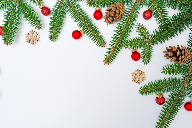 Christmas holiday composition with fir branches red balls pine cones and wooden snowflackes on white background