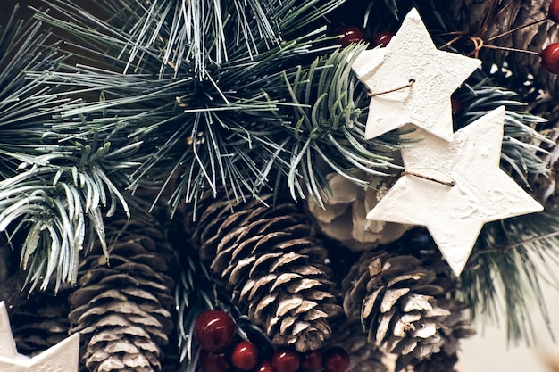 クリスマスの休日の装飾。赤いベリー、スターキャンドル、雪のきらめくコーンのクリスマスモミの木のブランチは、テクスチャをクローズアップします。浅い焦点。クリスマスの縦の壁紙の概念