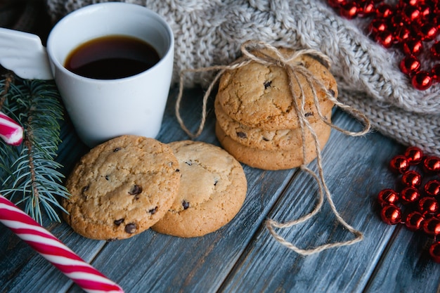 クリスマスホリデーフードスナックのコンセプト。木製の背景にチョコレートチップクッキーとお茶のマグカップ。季節の装飾。