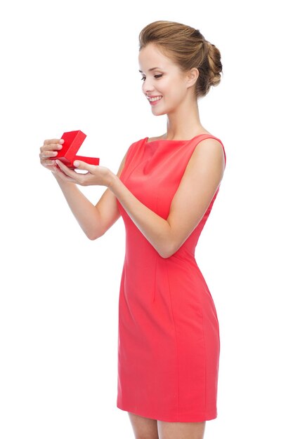 christmas, holiday, valentine's day and celebration concept - smiling young woman in red dress with gift box