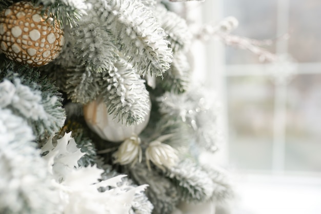 Рождественский праздник белая еловая ветка с игрушечным шариком возле окна