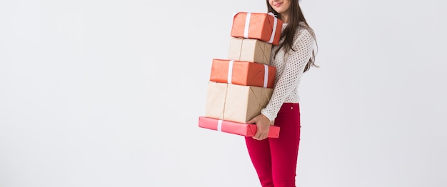 Concetto di natale e festività - primo piano di una donna che tiene in mano una pila di scatole regalo su sfondo bianco con spazio per le copie