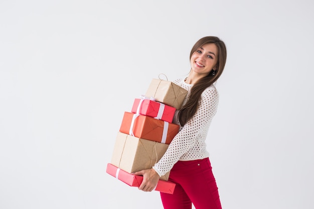 Christmas and holidays concept - woman with many gifts on white background with copy space