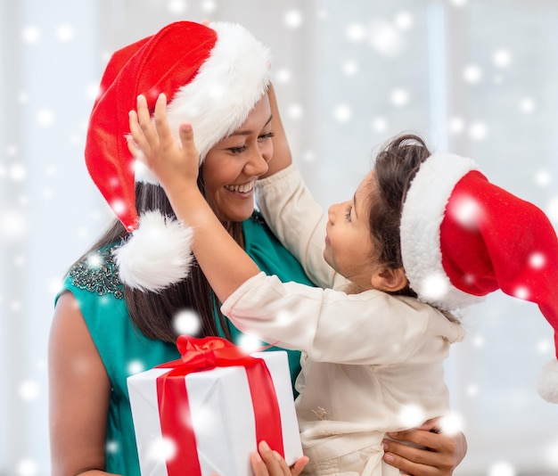 christmas, holidays, family and people concept - happy mother and child girl with gift box at home