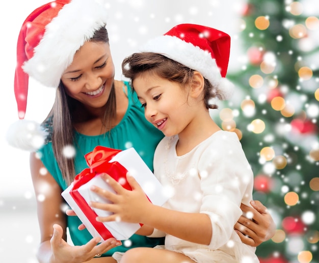 christmas, holidays, family and people concept - happy mother and child girl with gift box at home